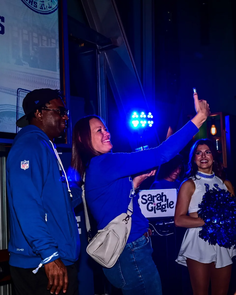 A fan taking a photograph at the Colts party beside the DJ setup
