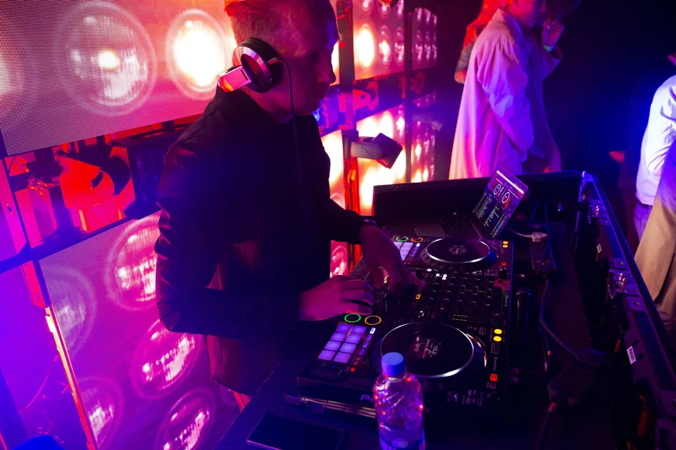 DJ mixing live at the decks under pink stage lighting