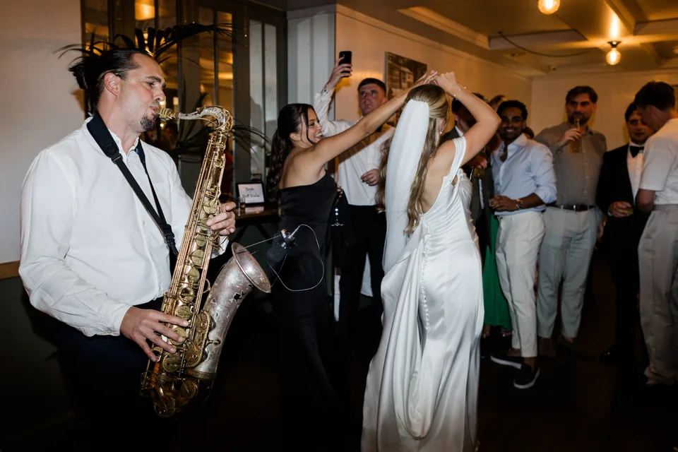 Bride celebrating beside a live saxophonist at The Italian Greyhound