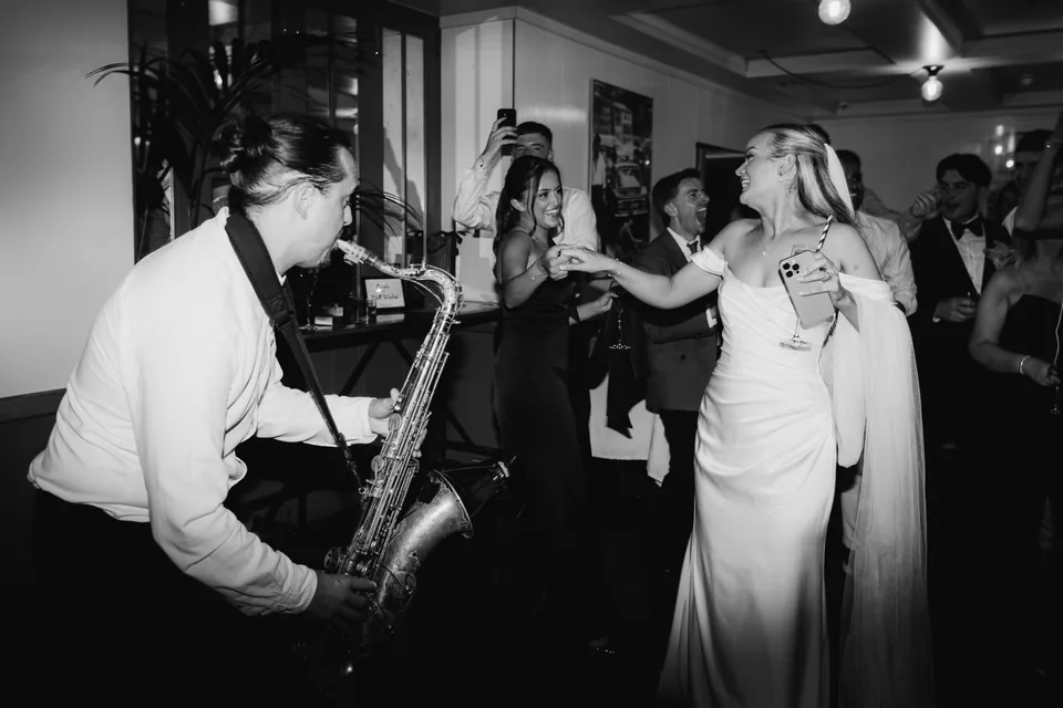 Black-and-white wedding photograph of the bride and live saxophonist