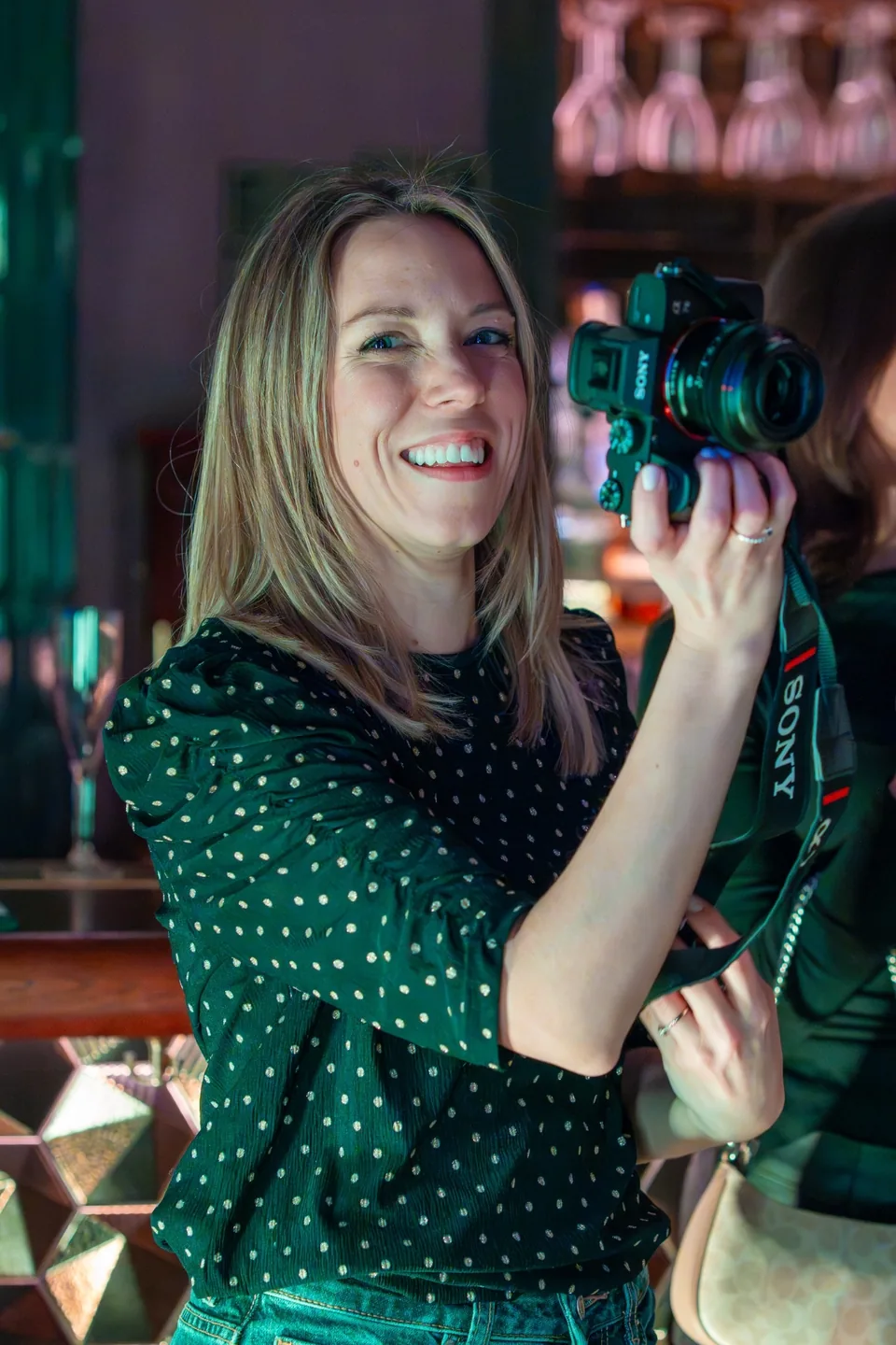 Photographer Vicky Foxx smiling and holding her camera at an event